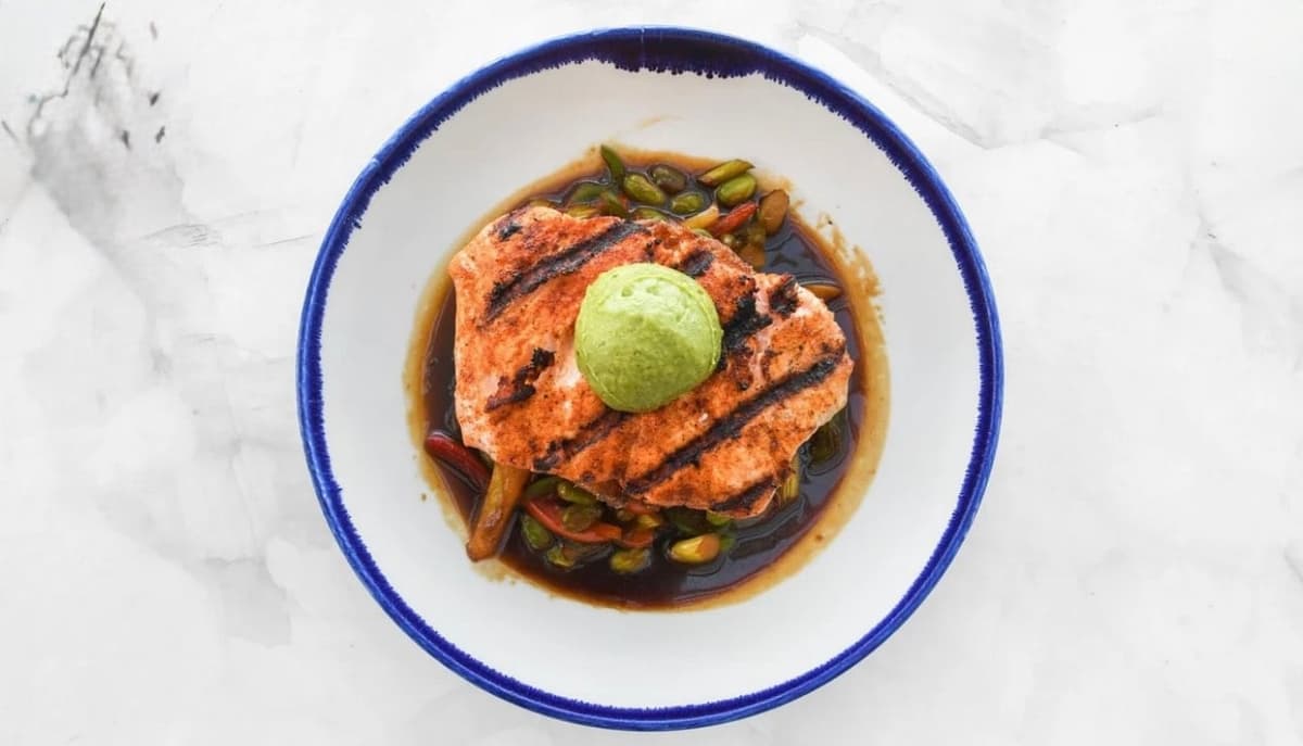 Sriracha dusted grilled salmon over ponzu roasted vegetables and a sticky rice cake, (mango, ginger, jalapeño, bell pepper, onion & sushi rice), finished with an avocado purée